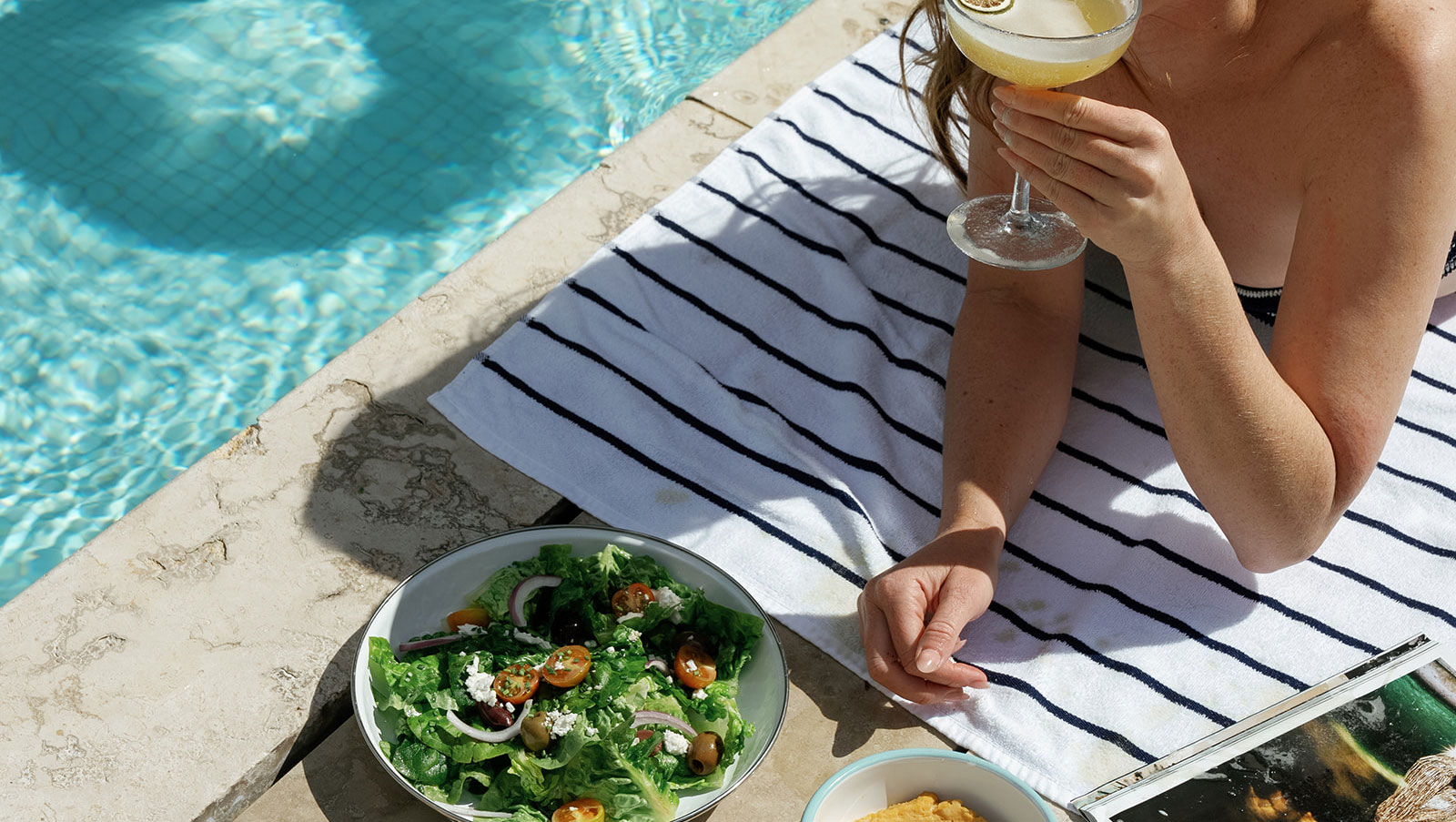 Guest with cocktail and salad by the pool