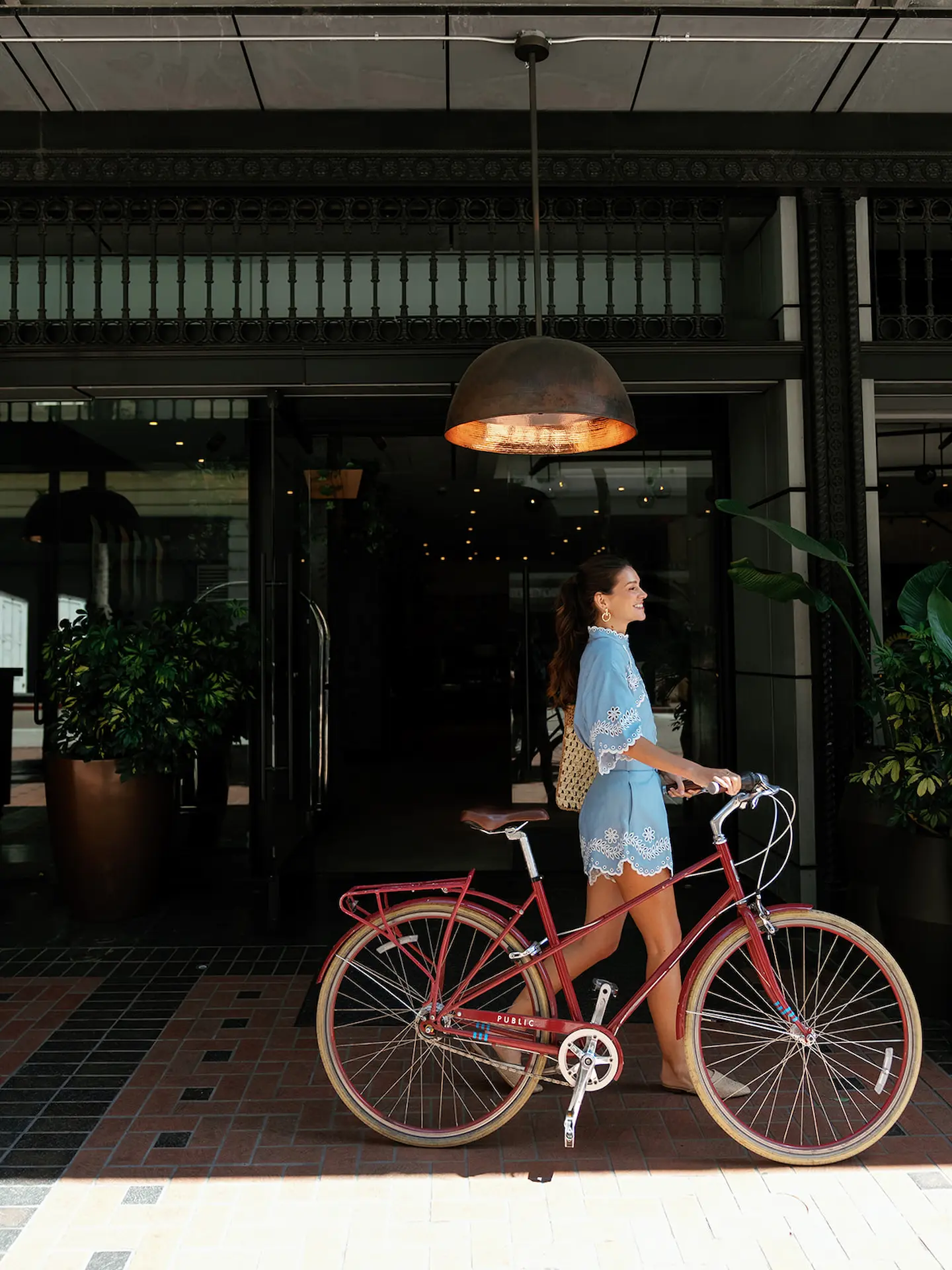 Girl walking out of the Alma hotel with her bike, ready for an adventure